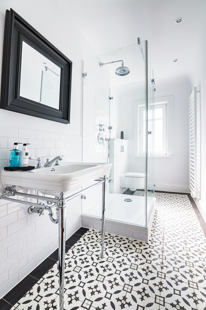 Inredning av ett klassiskt litet badrum med dusch, med en toalettstol med separat cisternkåpa, vita väggar, klinkergolv i keramik, bänkskiva i rostfritt stål, ett undermonterad handfat, svart och vit kakel och tunnelbanekakel