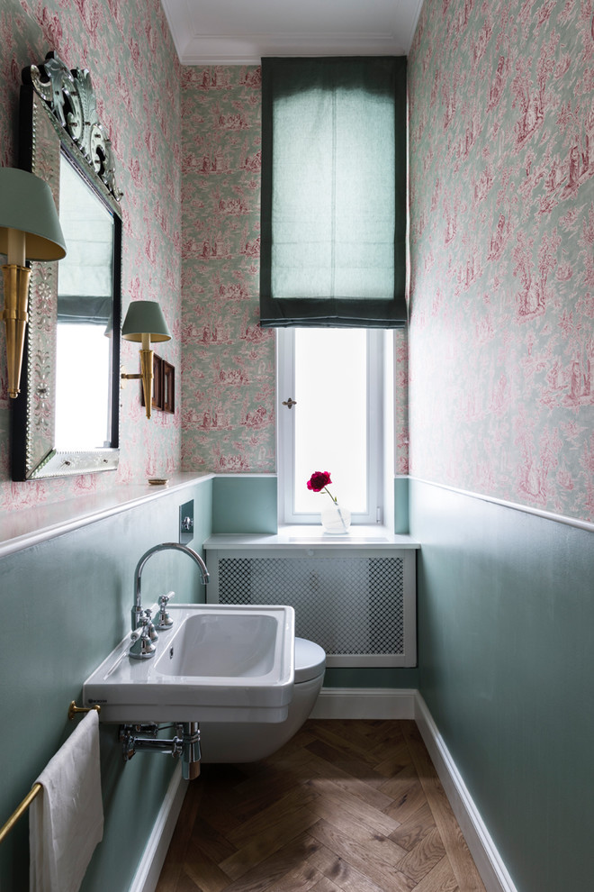 Imagen de cuarto de baño clásico pequeño con sanitario de pared, paredes azules, suelo de madera en tonos medios, lavabo suspendido, encimera de acrílico y suelo marrón