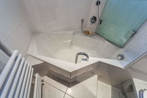 Ispirazione per una piccola stanza da bagno padronale minimal con vasca ad angolo, pareti bianche e pavimento bianco