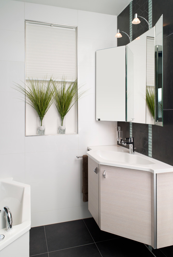 Foto di una piccola stanza da bagno contemporanea con ante lisce, ante beige, pareti bianche, lavabo integrato, pavimento nero, vasca da incasso, piastrelle nere e top in superficie solida