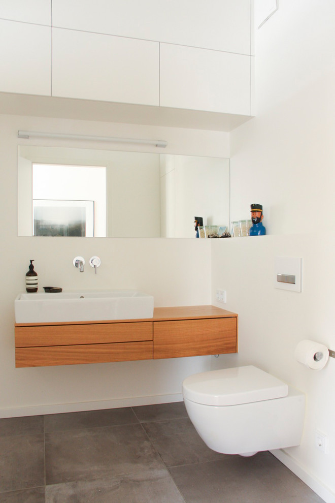 Свежая идея для дизайна: ванная комната среднего размера в стиле модернизм с плоскими фасадами, светлыми деревянными фасадами, ванной в нише, душем над ванной, раздельным унитазом, белой плиткой, белыми стенами, светлым паркетным полом, душевой кабиной, настольной раковиной, столешницей из дерева, открытым душем и белой столешницей - отличное фото интерьера