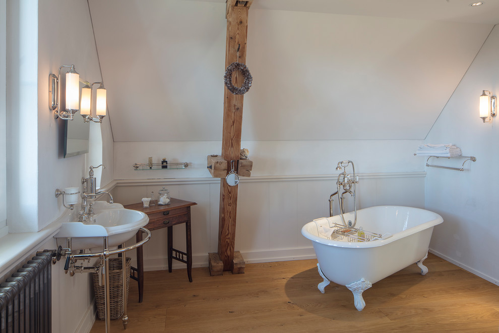 Mittelgroßes Modernes Duschbad mit Löwenfuß-Badewanne, weißen Fliesen, weißer Wandfarbe, hellem Holzboden, Waschtischkonsole und braunem Boden in München