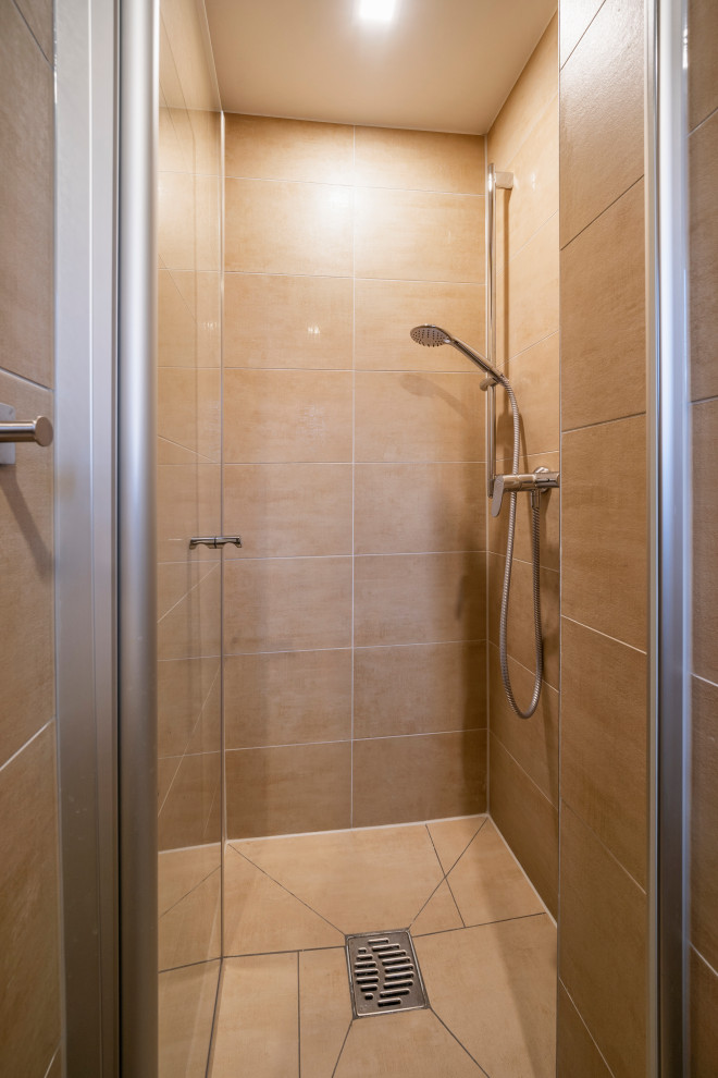Cette image montre une petite salle de bain minimaliste avec WC suspendus, un carrelage marron, un mur marron, un lavabo posé, un sol marron et une cabine de douche à porte battante.