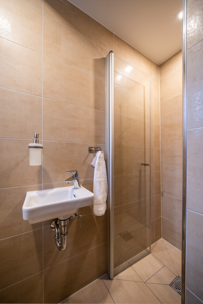 Cette photo montre une petite salle de bain moderne avec WC suspendus, un carrelage marron, un mur marron, un lavabo posé, un sol marron et une cabine de douche à porte battante.