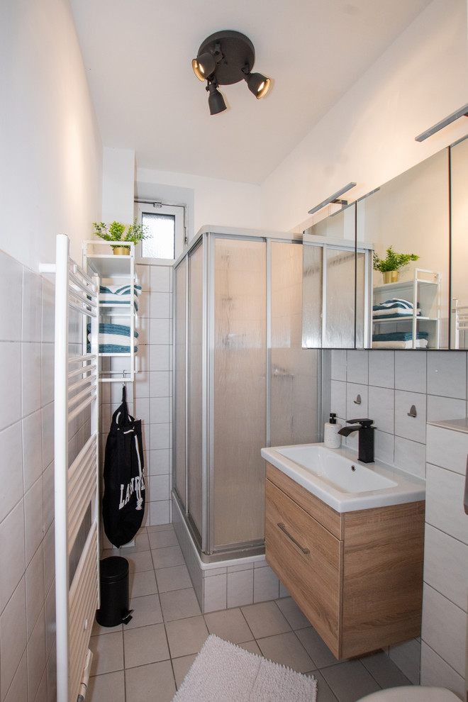 Modern inredning av ett litet vit vitt badrum med dusch, med svarta väggar, laminatgolv, brunt golv, släta luckor, skåp i mörkt trä, vit kakel, keramikplattor och bänkskiva i akrylsten