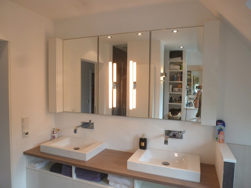 Exemple d'une petite salle d'eau tendance avec un placard à porte plane, des portes de placard blanches, un bain bouillonnant, une douche à l'italienne, un carrelage gris, un mur blanc et une vasque.
