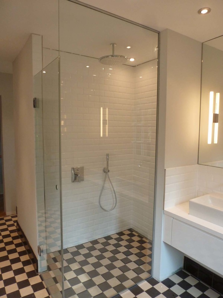 Bild på ett vintage vit vitt badrum, med vita skåp, en kantlös dusch, vit kakel, tunnelbanekakel, ett fristående handfat och svart golv