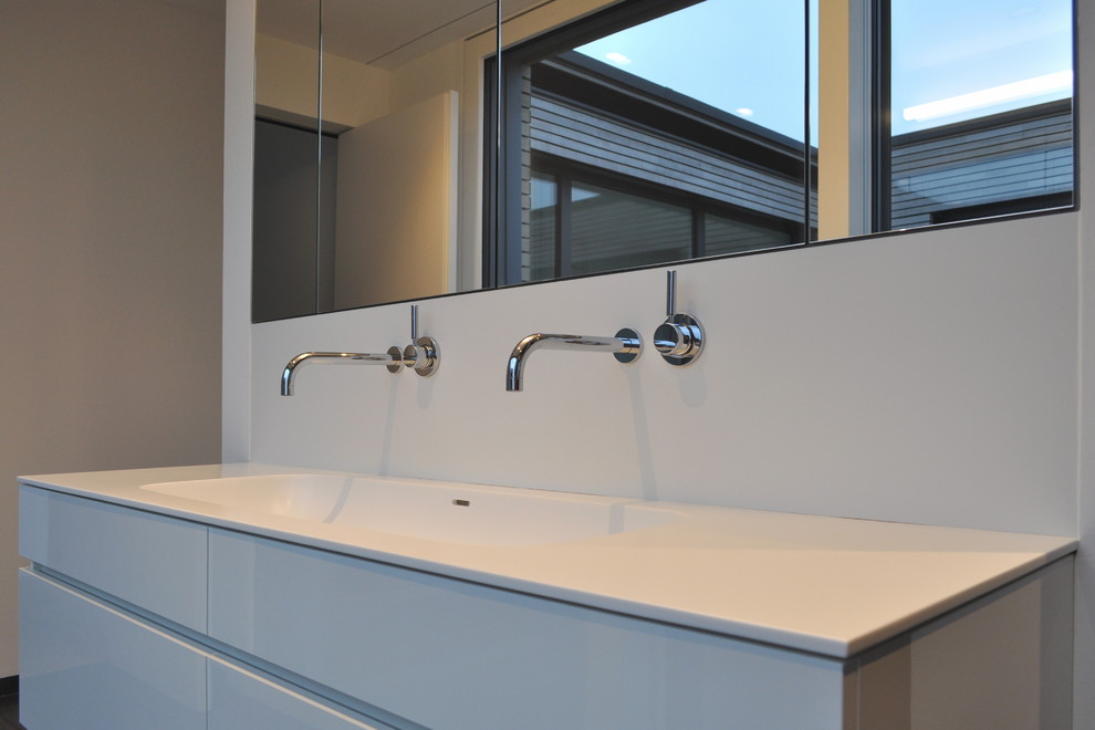Photo of a contemporary bathroom in Essen with white cabinets, an integrated sink and solid surface worktops.