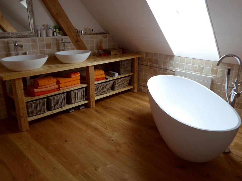 Foto på ett lantligt badrum, med ett fristående badkar, mellanmörkt trägolv och vita väggar