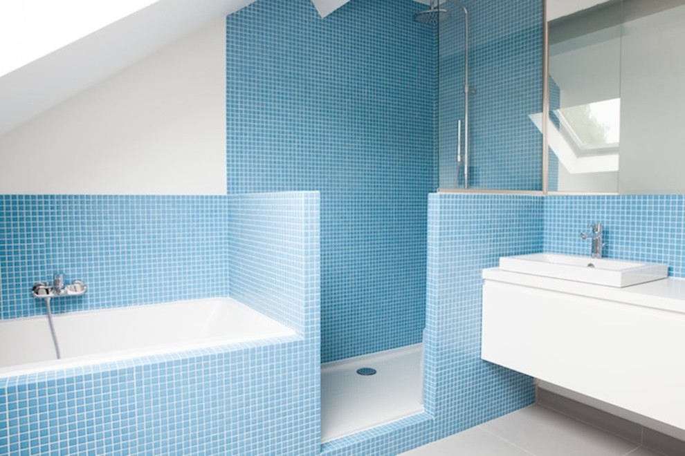 Foto på ett funkis badrum, med släta luckor, vita skåp, ett platsbyggt badkar, en dusch i en alkov, blå kakel, mosaik, vita väggar och ett fristående handfat