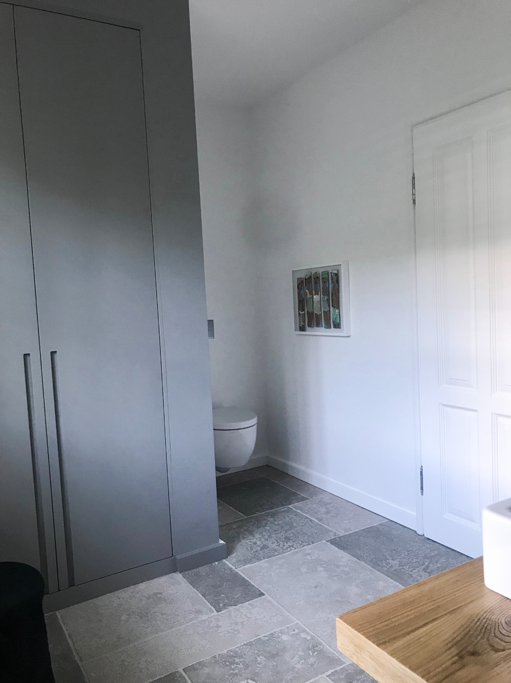 Modelo de cuarto de baño contemporáneo grande con bañera exenta, ducha a ras de suelo, suelo gris, paredes grises, aseo y ducha y ducha con puerta corredera