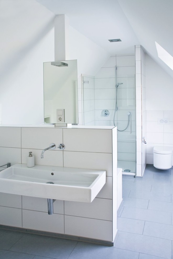 Foto de cuarto de baño actual con ducha a ras de suelo, sanitario de pared, baldosas y/o azulejos blancos, paredes blancas, aseo y ducha y lavabo suspendido