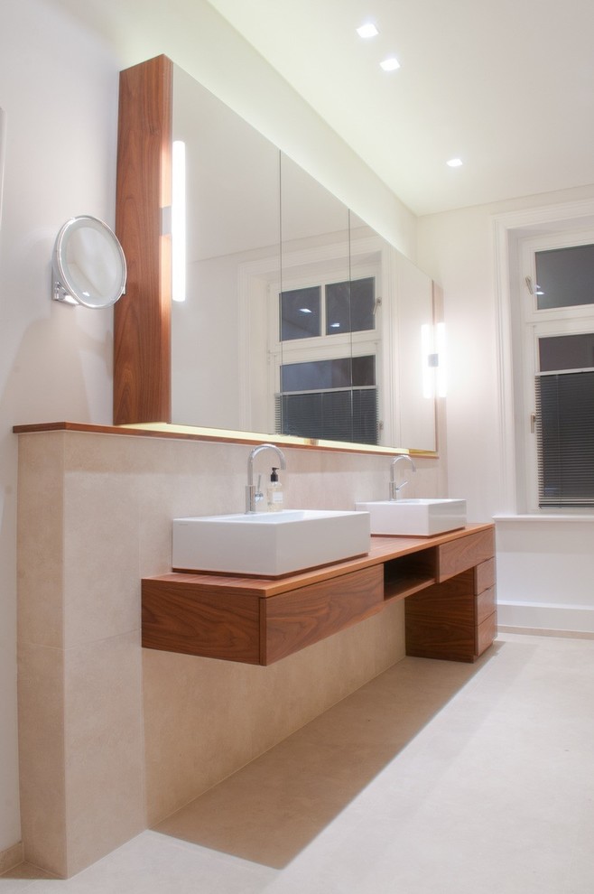 Пример оригинального дизайна: ванная комната в современном стиле с плоскими фасадами, фасадами цвета дерева среднего тона, бежевой плиткой, белыми стенами, настольной раковиной и столешницей из дерева
