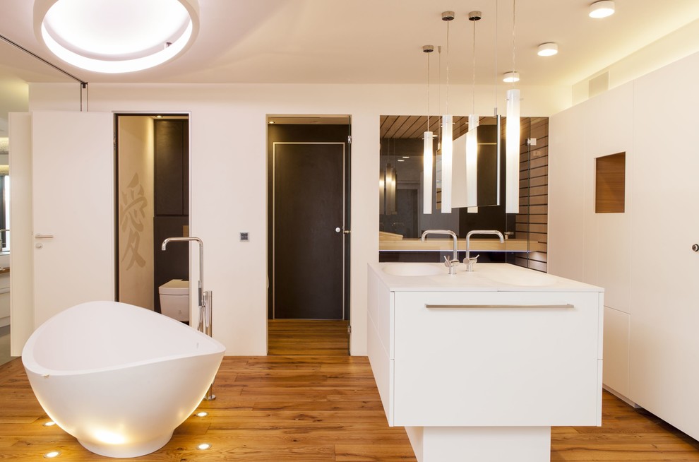 Huge trendy 3/4 medium tone wood floor freestanding bathtub photo in Stuttgart with white cabinets and white walls
