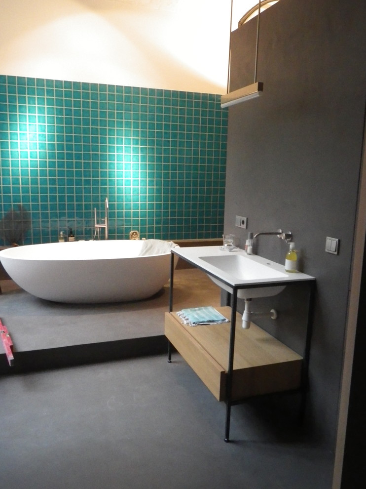 Foto på ett mellanstort funkis badrum med dusch, med ett fristående badkar, en kantlös dusch, blå kakel, keramikplattor, grå väggar och betonggolv