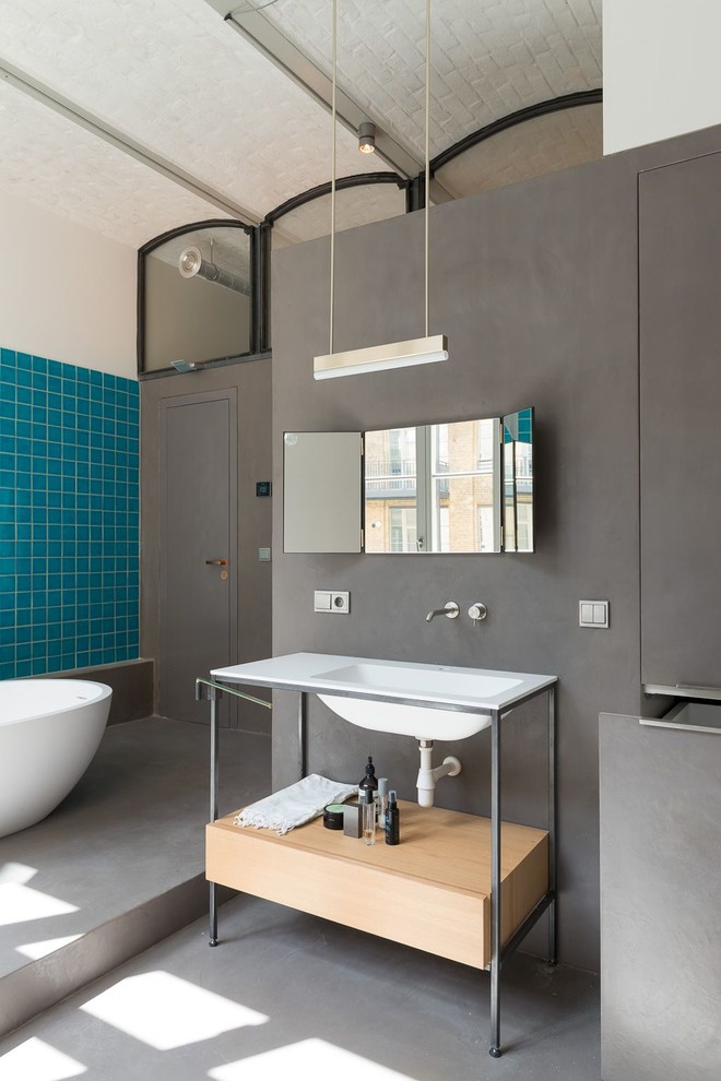 На фото: ванная комната среднего размера в современном стиле с отдельно стоящей ванной, душем без бортиков, синей плиткой, керамической плиткой, серыми стенами, бетонным полом и душевой кабиной с