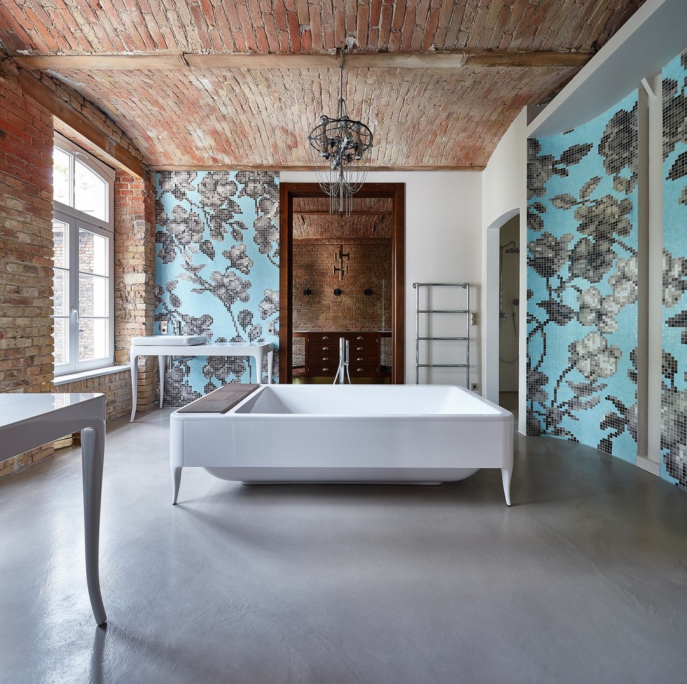 Ejemplo de cuarto de baño principal bohemio grande con bañera exenta, baldosas y/o azulejos de vidrio, suelo de cemento y lavabo sobreencimera