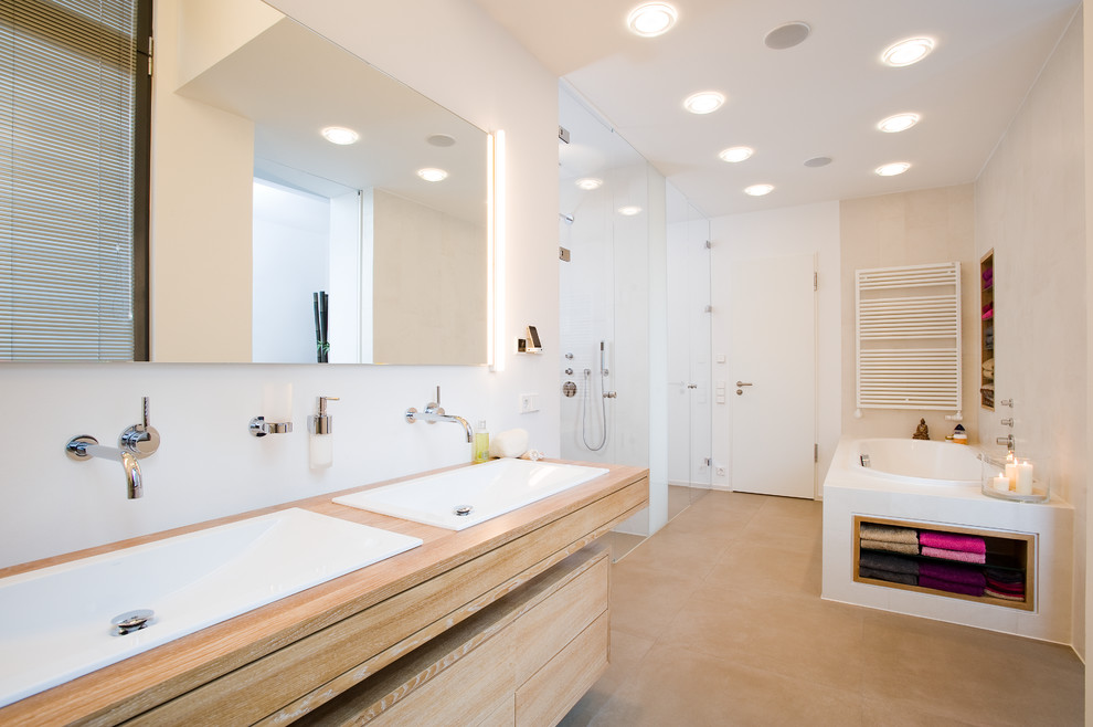 Exemple d'une grande douche en alcôve principale tendance en bois clair avec un lavabo posé, un placard à porte plane, un plan de toilette en bois, une baignoire posée et un mur blanc.