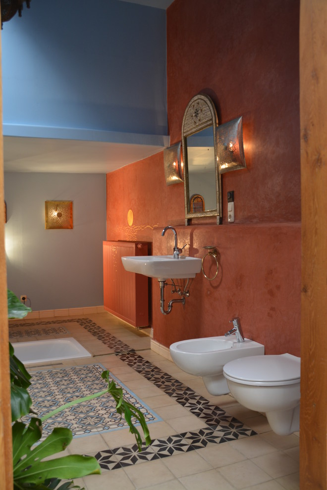 Immagine di una stanza da bagno mediterranea di medie dimensioni con vasca da incasso, doccia a filo pavimento, bidè, piastrelle blu, piastrelle di cemento, pareti rosse e lavabo sospeso