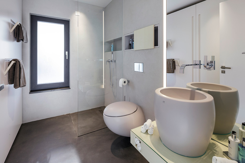 Ejemplo de cuarto de baño actual de tamaño medio con lavabo sobreencimera, ducha esquinera, paredes grises, suelo de cemento, sanitario de pared y aseo y ducha