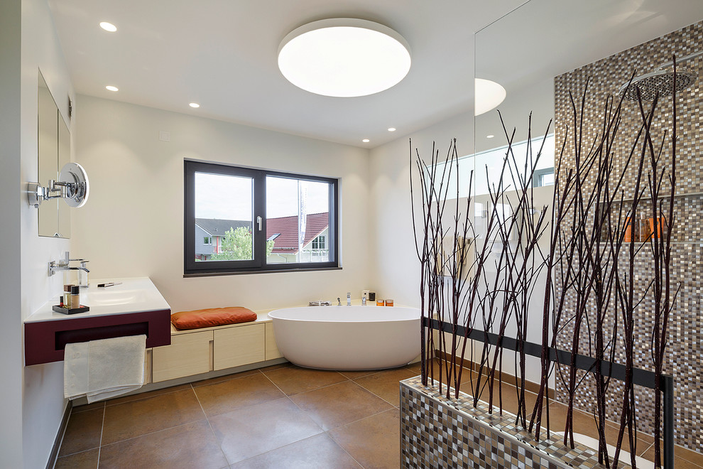 Diseño de cuarto de baño contemporáneo con lavabo integrado, armarios con paneles lisos, puertas de armario de madera clara, bañera exenta, ducha abierta, baldosas y/o azulejos marrones, baldosas y/o azulejos en mosaico y paredes blancas