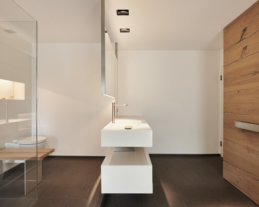 Bild på ett mellanstort funkis en-suite badrum, med vita skåp, en kantlös dusch, en vägghängd toalettstol, vita väggar och ett integrerad handfat