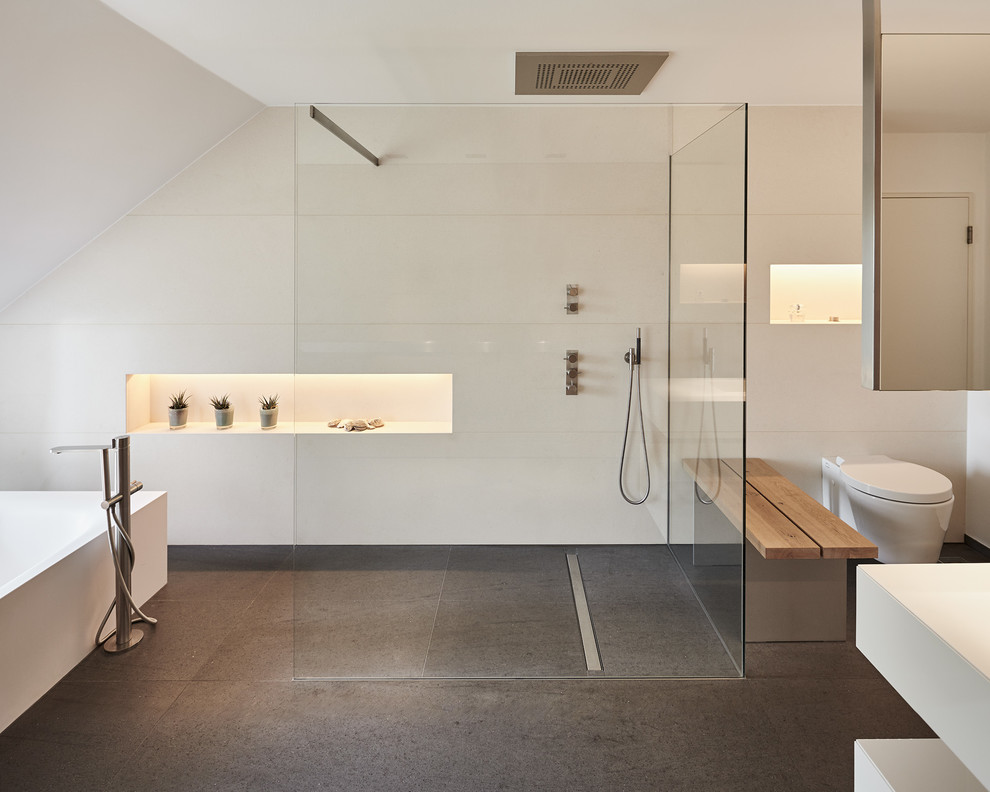Cette photo montre une salle de bain principale moderne de taille moyenne avec une baignoire indépendante, une douche à l'italienne, WC suspendus, un carrelage blanc, des carreaux de céramique et un mur blanc.