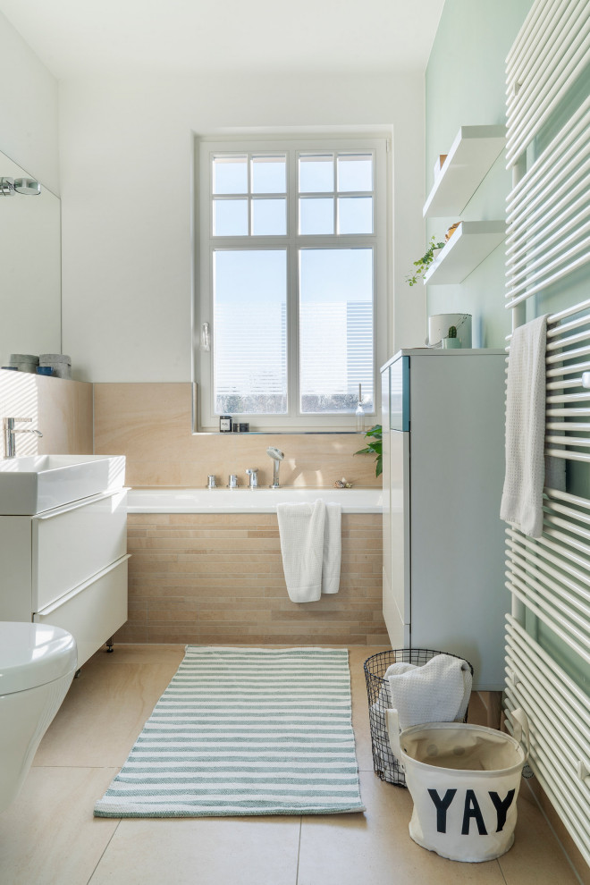 Immagine di una stanza da bagno minimal di medie dimensioni con ante turchesi, vasca da incasso, WC sospeso, piastrelle beige e lavabo integrato