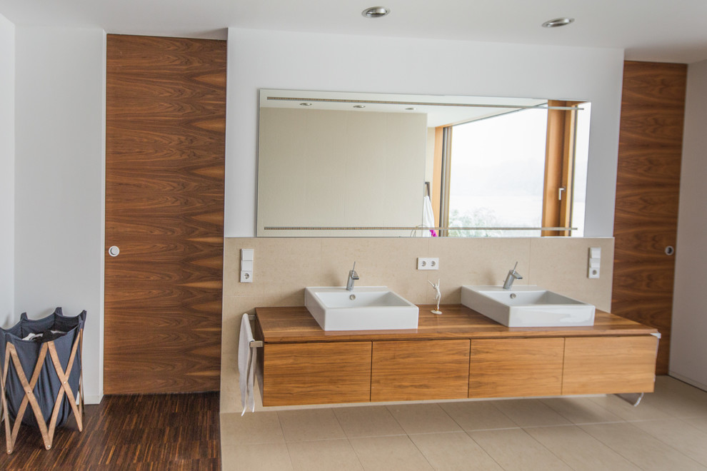 Modernes Badezimmer mit Aufsatzwaschbecken, Einbaubadewanne, bodengleicher Dusche, beigen Fliesen und Steinfliesen in Sonstige