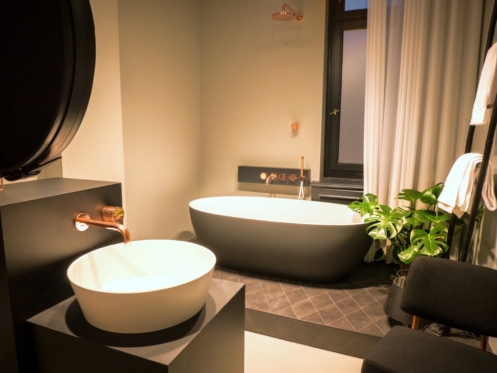 На фото: большая ванная комната в современном стиле с отдельно стоящей ванной, душем над ванной, бежевыми стенами и настольной раковиной