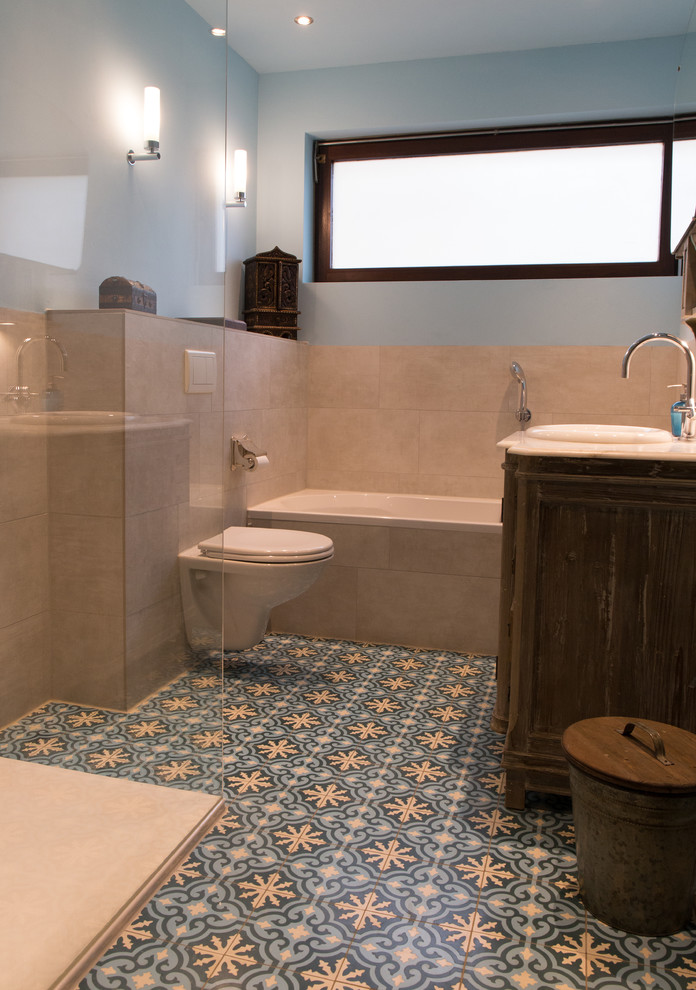 На фото: маленькая главная ванная комната в средиземноморском стиле с фасадами с выступающей филенкой, коричневыми фасадами, угловой ванной, душем без бортиков, раздельным унитазом, бежевой плиткой, керамической плиткой, синими стенами, полом из керамической плитки, монолитной раковиной, мраморной столешницей, разноцветным полом и открытым душем для на участке и в саду