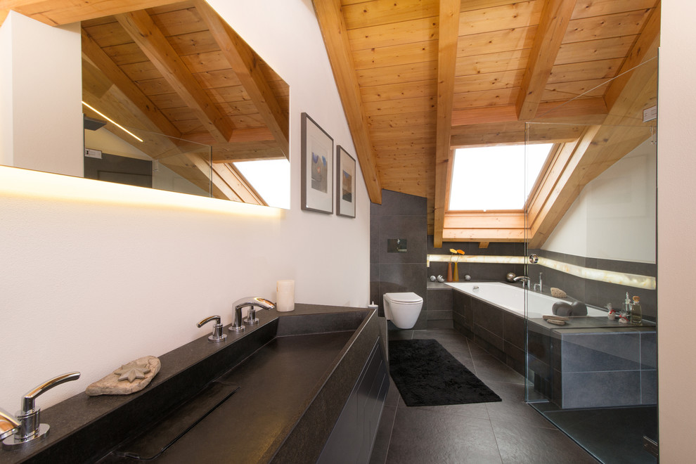 Photo of a large contemporary ensuite bathroom in Stuttgart with a trough sink, a submerged bath, grey tiles, white walls, a built-in shower, a wall mounted toilet, stone slabs and slate flooring.