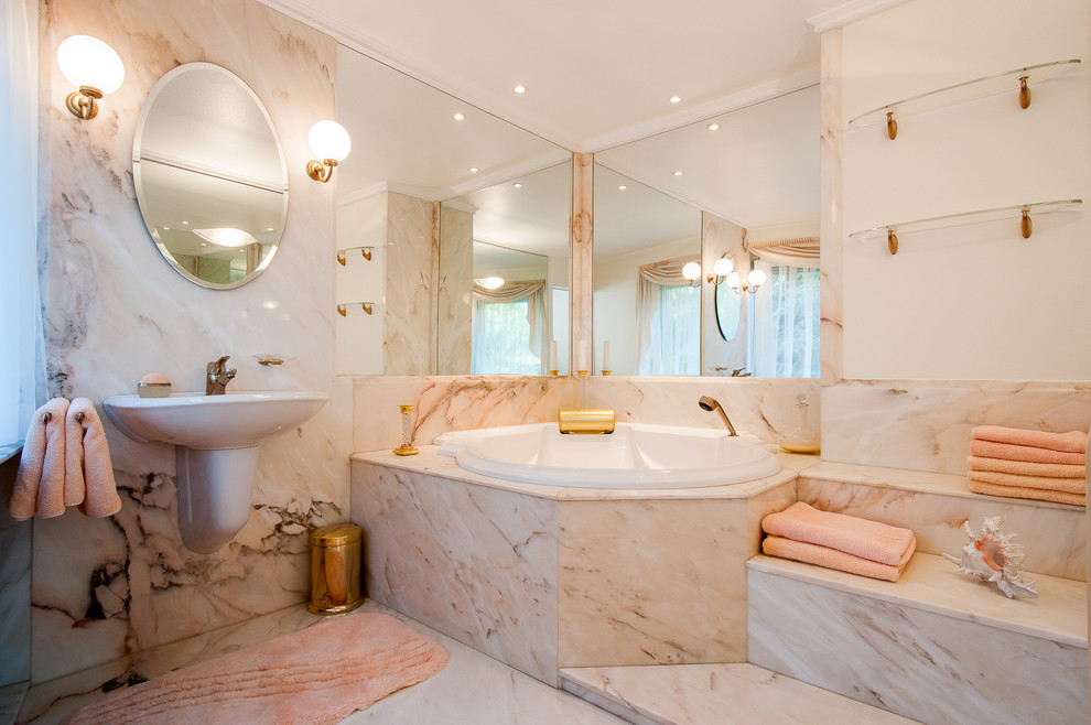 Large contemporary bathroom in Berlin with a wall-mounted sink, marble flooring, a corner bath, stone slabs, pink walls and beige tiles.