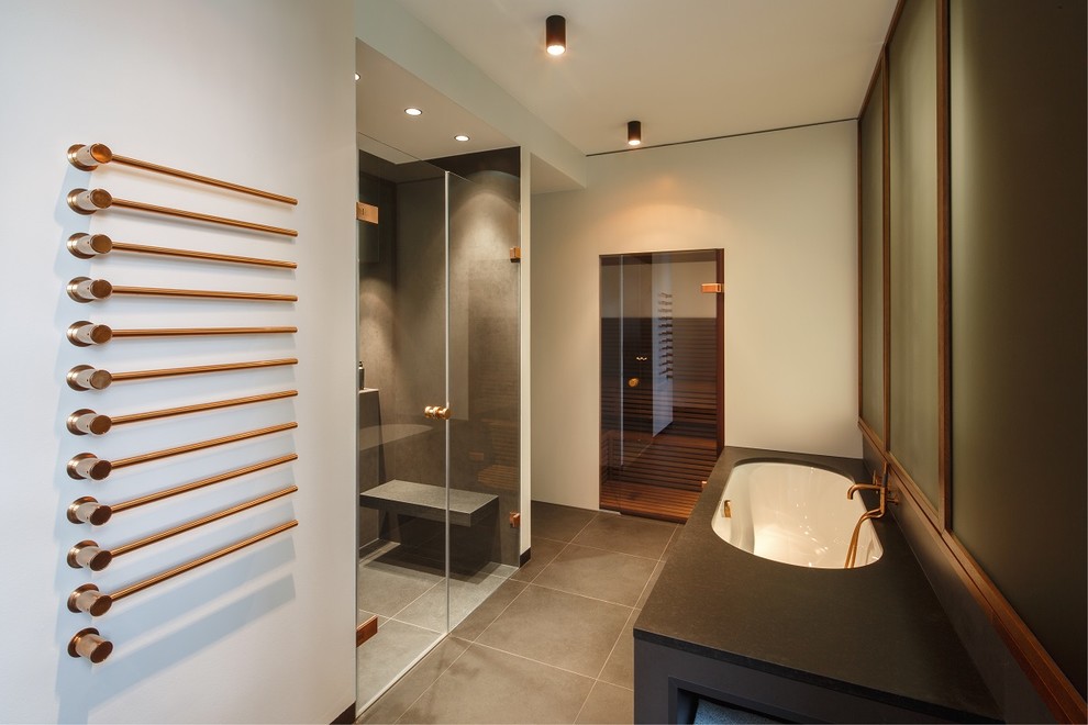 Inspiration for a mid-sized contemporary 3/4 limestone tile limestone floor and gray floor bathroom remodel in Berlin with flat-panel cabinets, gray cabinets, a two-piece toilet, gray walls, a drop-in sink, granite countertops and a hinged shower door