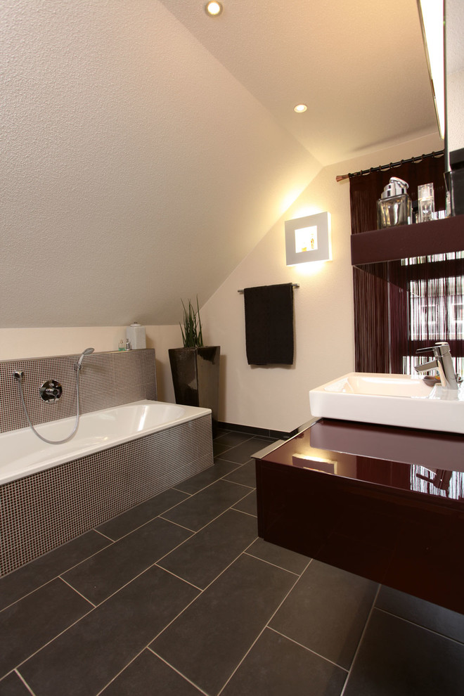 Modernes Badezimmer mit roten Schränken, Einbaubadewanne, braunen Fliesen, weißer Wandfarbe, grauem Boden und roter Waschtischplatte in Sonstige