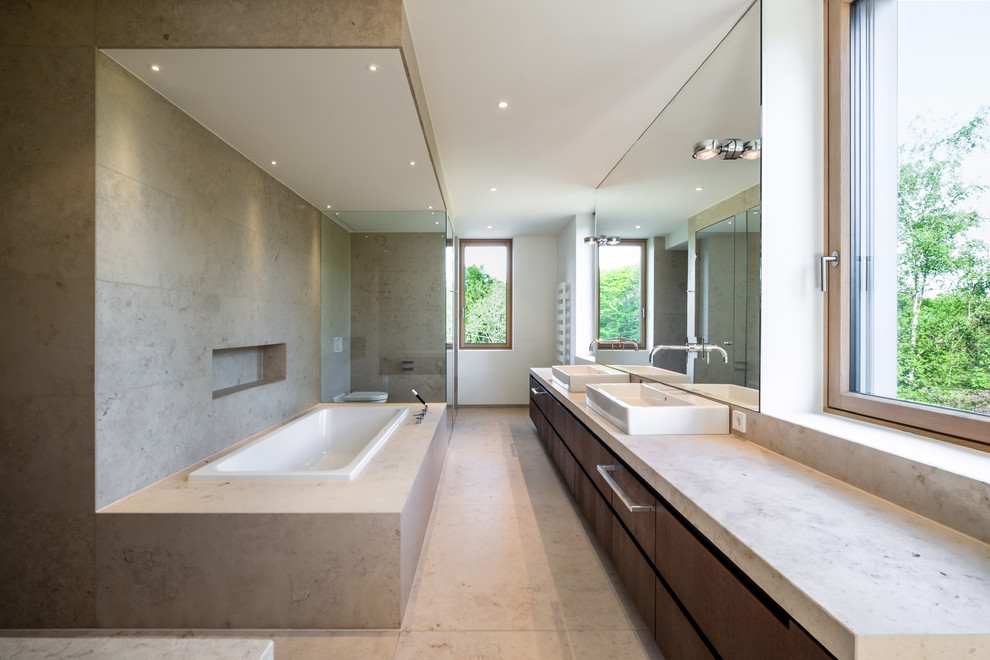 Пример оригинального дизайна: большая ванная комната в стиле модернизм с плоскими фасадами, темными деревянными фасадами, накладной ванной, раздельным унитазом, бежевой плиткой, белыми стенами, настольной раковиной, бежевым полом и бежевой столешницей