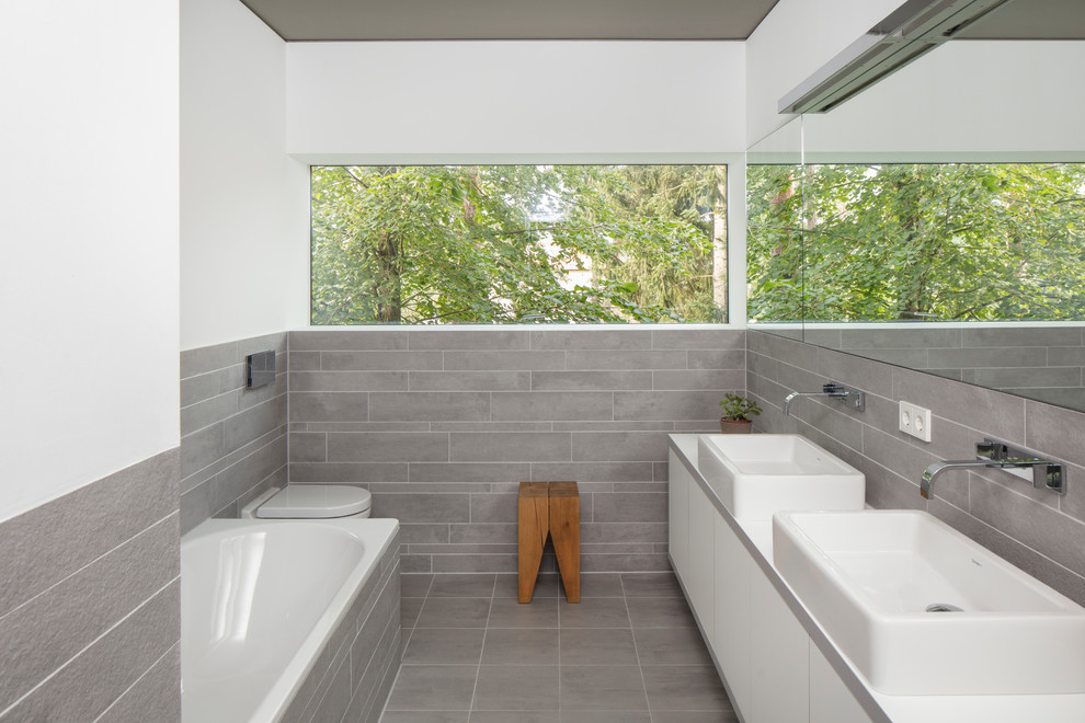 Idéer för små funkis badrum med dusch, med släta luckor, vita skåp, ett hörnbadkar, en vägghängd toalettstol, beige kakel, vita väggar, ett fristående handfat och beiget golv