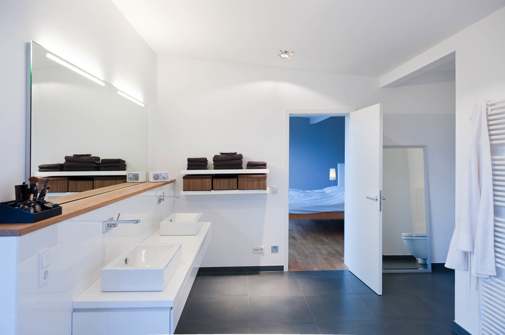 Großes Modernes Badezimmer En Suite mit flächenbündigen Schrankfronten, weißen Schränken, grauen Fliesen, weißer Wandfarbe, Keramikboden und Aufsatzwaschbecken in Sonstige