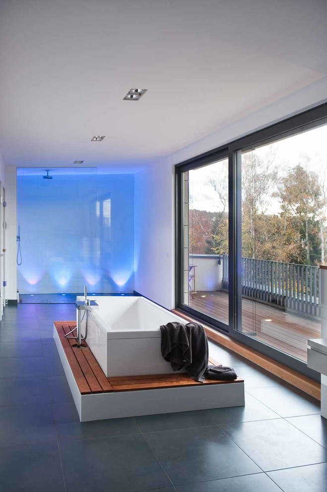 Immagine di un'ampia stanza da bagno contemporanea con vasca freestanding, doccia a filo pavimento, piastrelle grigie e pareti bianche