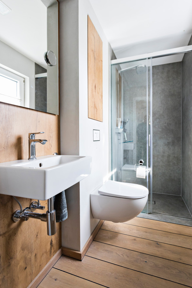 Réalisation d'une douche en alcôve design en bois avec WC suspendus, un carrelage gris, un mur blanc, un sol en bois brun, une vasque, un sol marron, une cabine de douche à porte coulissante et meuble simple vasque.