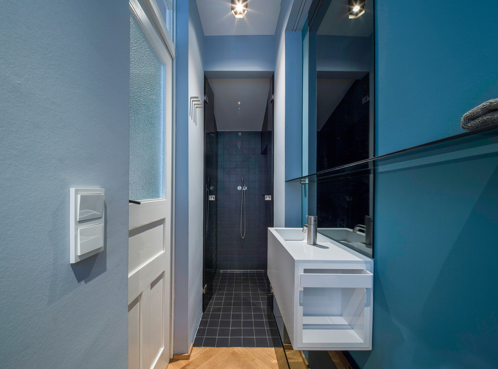 Immagine di una stretta e lunga stanza da bagno minimal di medie dimensioni con nessun'anta, ante bianche, piastrelle blu, piastrelle in ceramica, pareti blu, pavimento con piastrelle in ceramica, lavabo integrato e top in superficie solida