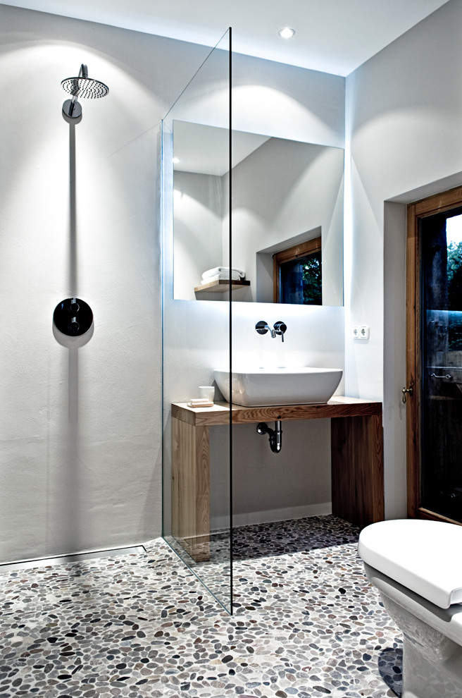 Inredning av ett modernt litet brun brunt badrum, med ett fristående handfat, skåp i mellenmörkt trä, träbänkskiva, en öppen dusch, grå väggar, klinkergolv i småsten, kakel i småsten och med dusch som är öppen