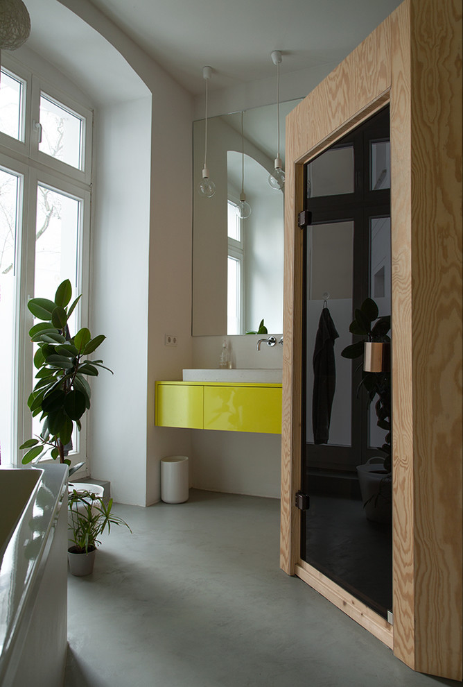 Mittelgroßes Modernes Badezimmer mit flächenbündigen Schrankfronten, gelben Schränken, weißer Wandfarbe, Betonboden und Aufsatzwaschbecken in Berlin