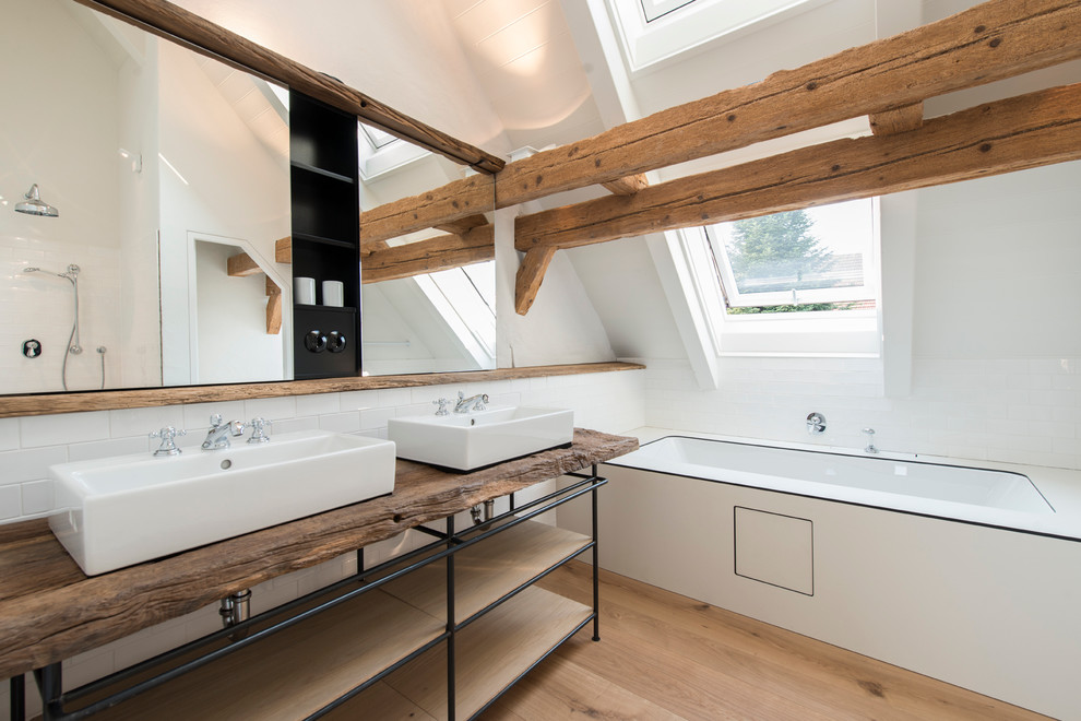 ミュンヘンにある広いコンテンポラリースタイルのおしゃれな浴室 (ベッセル式洗面器、アルコーブ型浴槽、オープンシェルフ、オープン型シャワー、白いタイル、サブウェイタイル、白い壁、無垢フローリング、木製洗面台) の写真