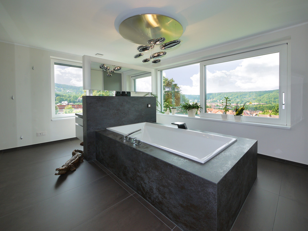 Aménagement d'une grande salle de bain contemporaine avec une baignoire posée, un carrelage noir et un mur blanc.