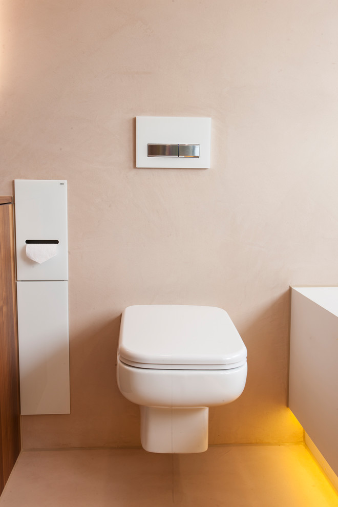 Cette image montre un grand WC suspendu rustique en bois brun avec un placard à porte plane, un mur beige, un lavabo posé, un plan de toilette en surface solide et un plan de toilette marron.