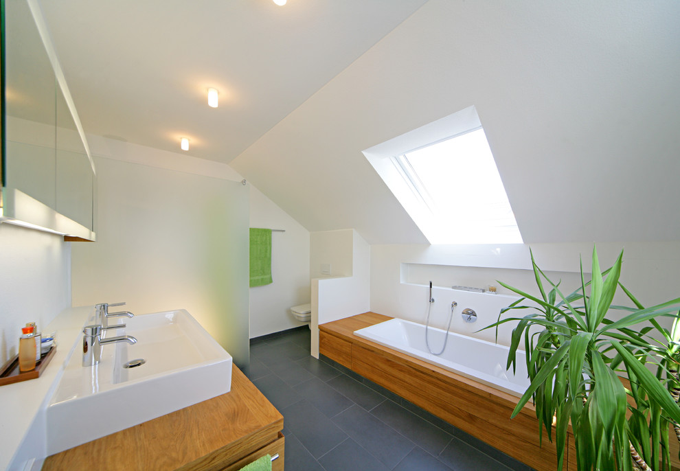 Exempel på ett modernt badrum med dusch, med skåp i mellenmörkt trä, ett platsbyggt badkar, en kantlös dusch, en vägghängd toalettstol, svart kakel och vita väggar