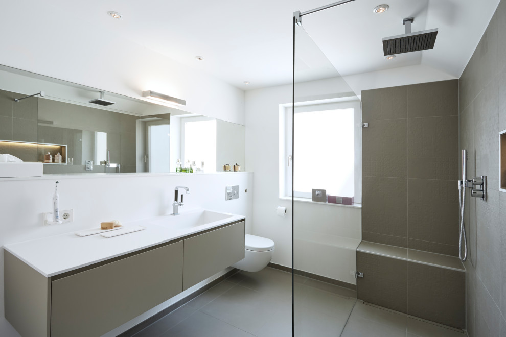 Идея дизайна: ванная комната среднего размера в современном стиле с плоскими фасадами, серыми фасадами, душем без бортиков, раздельным унитазом, серой плиткой, белыми стенами, душевой кабиной, столешницей из искусственного камня, серым полом, открытым душем и белой столешницей