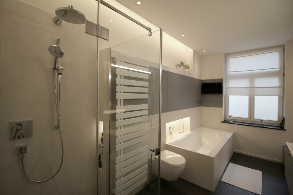 Large contemporary bathroom in Cologne with flat-panel cabinets, grey cabinets, a built-in bath, a wall mounted toilet, white tiles, ceramic tiles, white walls, an integrated sink and grey floors.