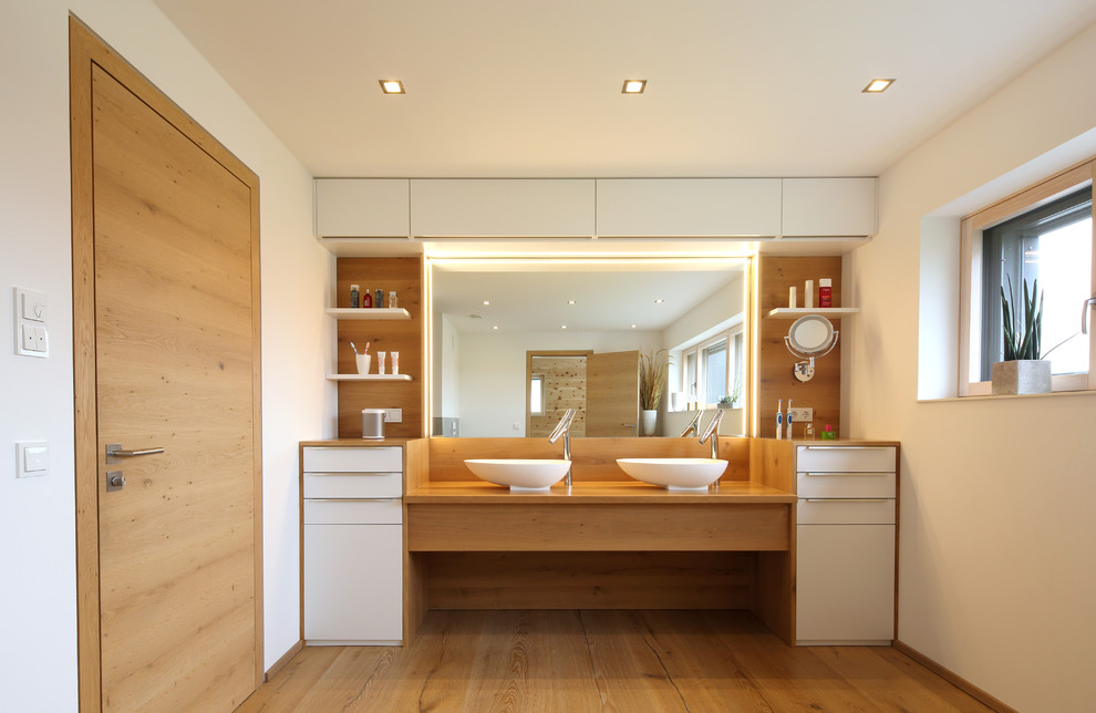 Idéer för ett stort modernt badrum med dusch, med skåp i ljust trä, ett fristående badkar, en kantlös dusch, vita väggar, ljust trägolv, ett fristående handfat och med dusch som är öppen